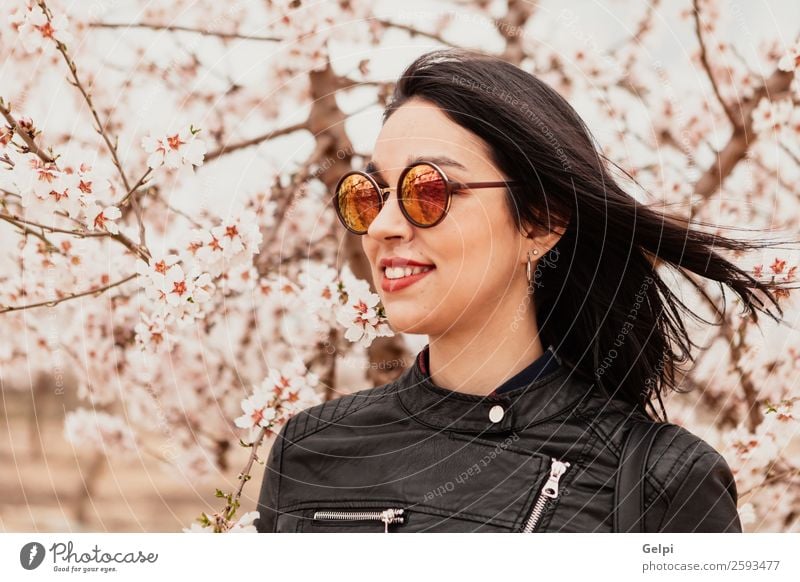 Brünettes Mädchen Stil Glück schön Gesicht Garten Mensch Frau Erwachsene Natur Baum Blume Blüte Park Mode Jacke Leder Sonnenbrille brünett Lächeln Fröhlichkeit