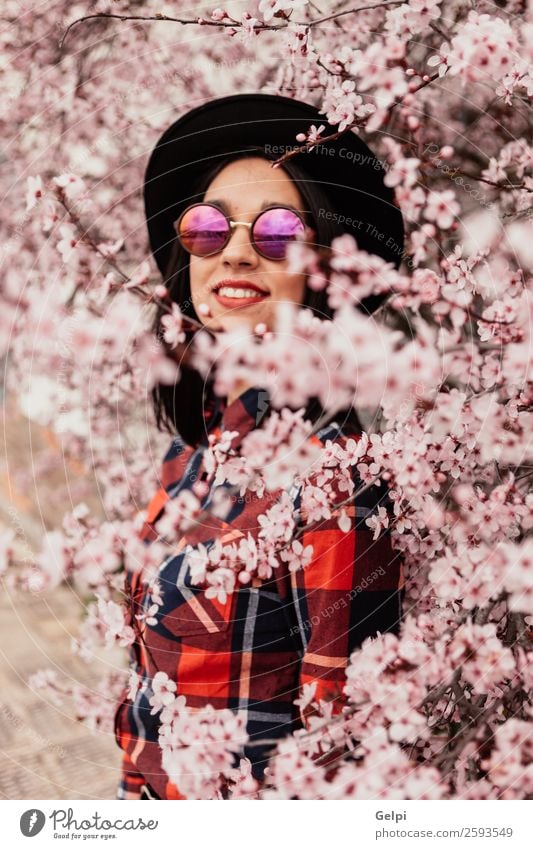 Brünettes Mädchen Stil Glück schön Gesicht Garten Mensch Frau Erwachsene Natur Baum Blume Blüte Park Mode Sonnenbrille Hut brünett Lächeln Fröhlichkeit frisch