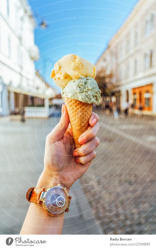 Frau hält grüne und gelbe Eiscreme in der Hand. Lebensmittel Milcherzeugnisse Dessert Speiseeis Süßwaren Essen Fastfood Lifestyle Stil Freude