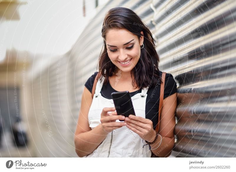 Lächelndes Mädchen, das mit ihrem Smartphone im Freien benutzt. Glück schön Haare & Frisuren Telefon PDA Technik & Technologie Mensch feminin Junge Frau