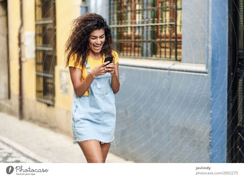 Afrikanische Frau, die auf der Straße geht und ihr Smartphone ansieht. Lifestyle Stil Glück schön Haare & Frisuren Telefon PDA Technik & Technologie Mensch