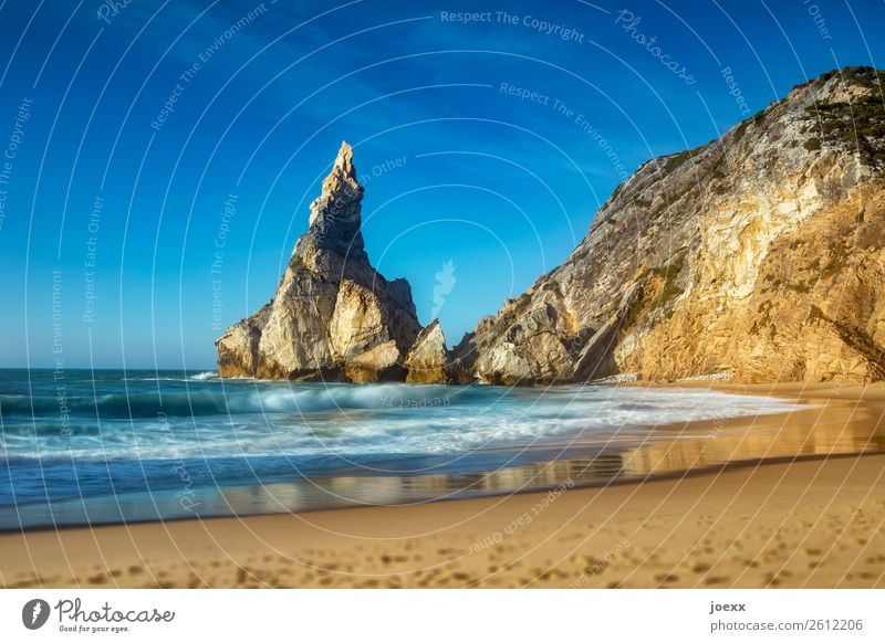 Großer spitzer Felsen an Küste mit Sandstrand mit leichten Wellen Felsenküste Meer Strand Himmel Landschaft Horizont Schönes Wetter Menschenleer Außenaufnahme