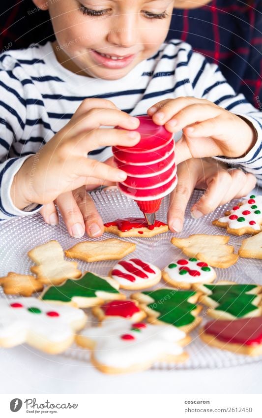 Kleines Kind schmückt Weihnachtsgebäck am Weihnachtstag Teigwaren Backwaren Freude Glück Dekoration & Verzierung Tisch Küche Feste & Feiern Weihnachten & Advent