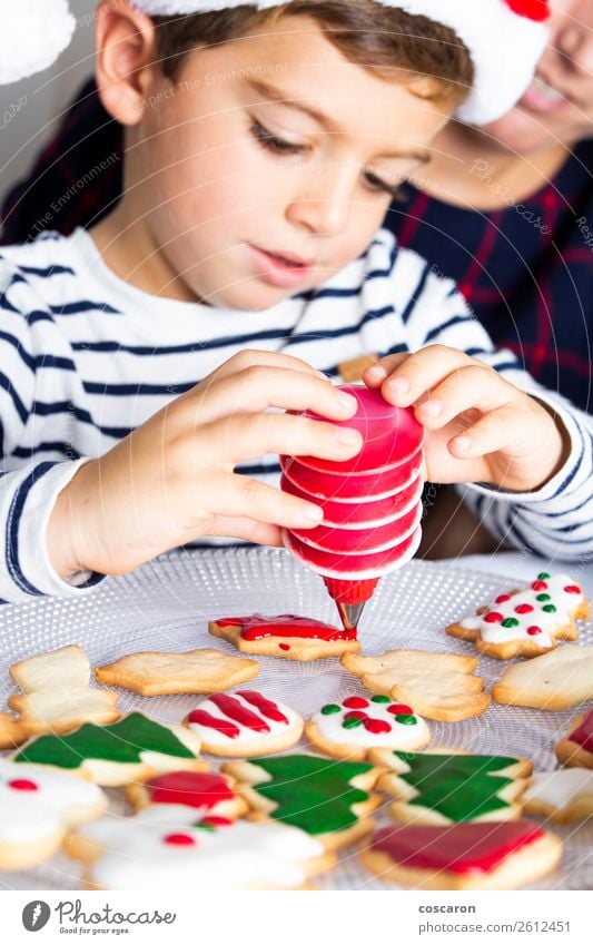 Kleines Kind schmückt Weihnachtsgebäck am Weihnachtstag Teigwaren Backwaren Dessert Süßwaren Freude Glück Winter Winterurlaub Dekoration & Verzierung Tisch