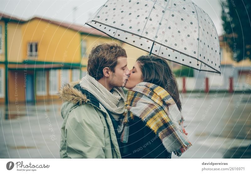 Junges Paar, das sich an einem regnerischen Tag unter dem Regenschirm im Freien küsst. Lifestyle Glück schön Winter Mensch Frau Erwachsene Mann