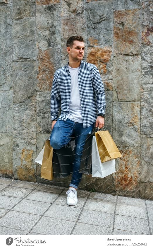 Junger Mann mit Einkaufstaschen Lifestyle kaufen Haare & Frisuren Erholung Freizeit & Hobby Mensch Erwachsene Mode T-Shirt Jeanshose Turnschuh stehen warten