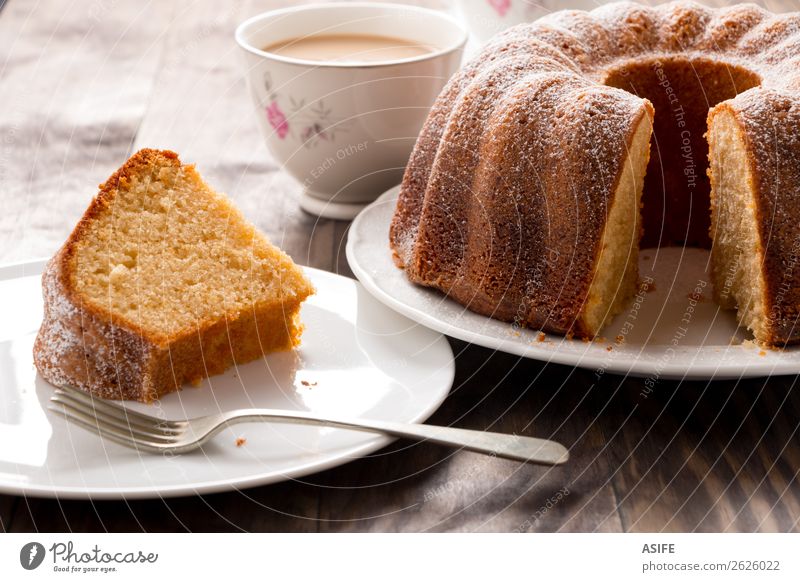 Biskuitkuchen mit Kaffee und Milch Joghurt Dessert Frühstück Tee Teller Gabel Tisch Holz frisch saftig braun Tradition Kuchen Bund Bundkuchen backen