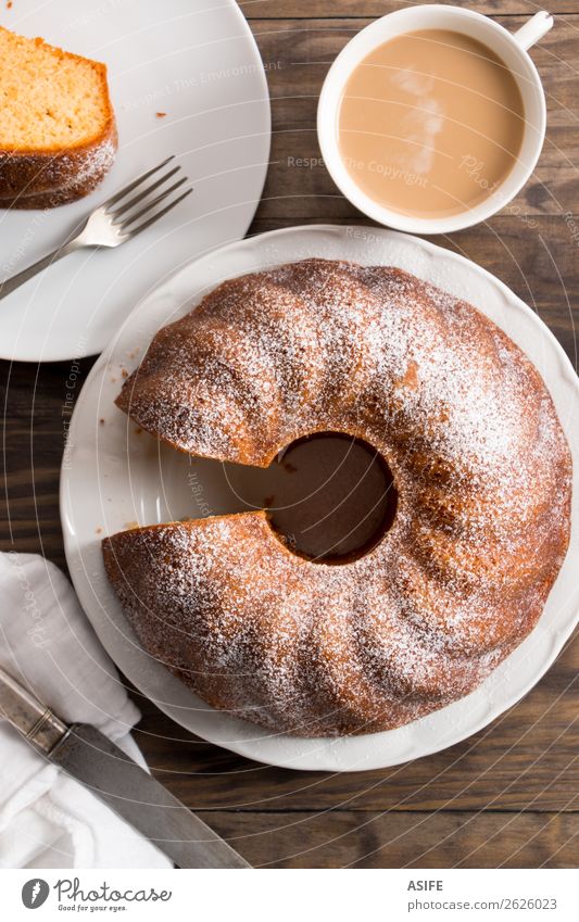 Biskuitkuchen mit Kaffee und Milch Joghurt Dessert Frühstück Tee Teller Gabel Tisch Holz frisch saftig braun Tradition Kuchen Bund Bundkuchen backen