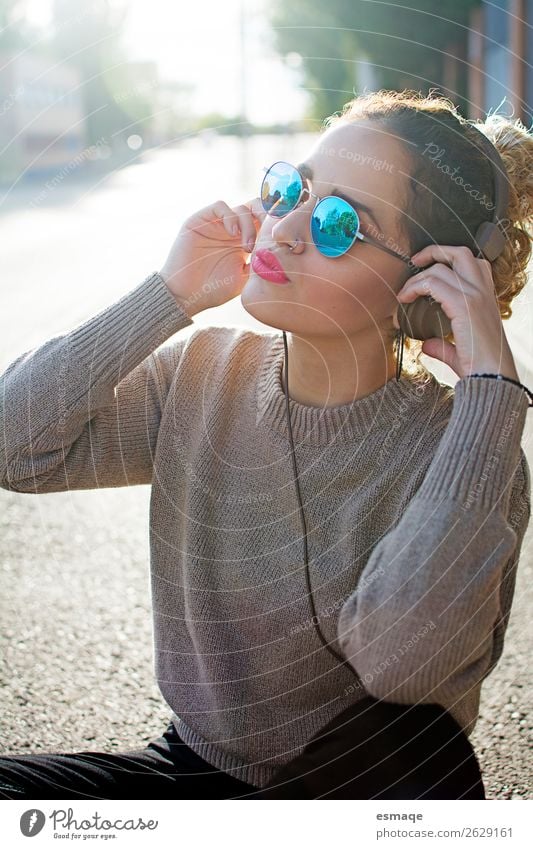 Junge Frau beim Musikhören auf der Straße Lifestyle Freude Wellness Leben Jugendliche Jugendkultur Musik hören Musiker Mode Accessoire Sonnenbrille Kopfhörer