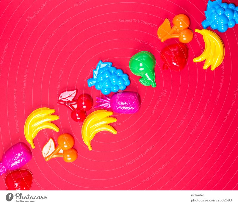 roter Hintergrund mit Plastikspielzeug für Kinder Frucht Apfel Freude Spielen Spielzeug Kunststoff hell niedlich oben blau gelb grün rosa Farbe Kreativität