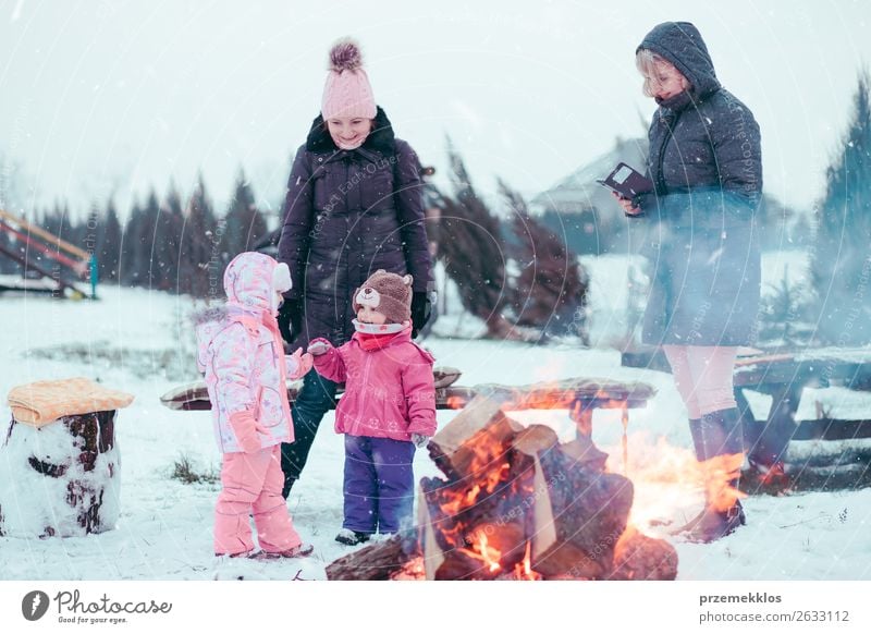 Die Familie, die Zeit zusammen verbringt, versammelt sich am Lagerfeuer. Lifestyle Freude Glück Freizeit & Hobby Winter Schnee Winterurlaub Garten Kind Mensch