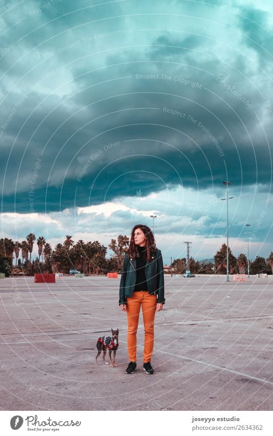 Frau mit ihrem Hund unter einer Sturmwolke. Lifestyle Winter Mensch Erwachsene Himmel Horizont Herbst Unwetter Regen Jacke Leder brünett stehen dunkel klein