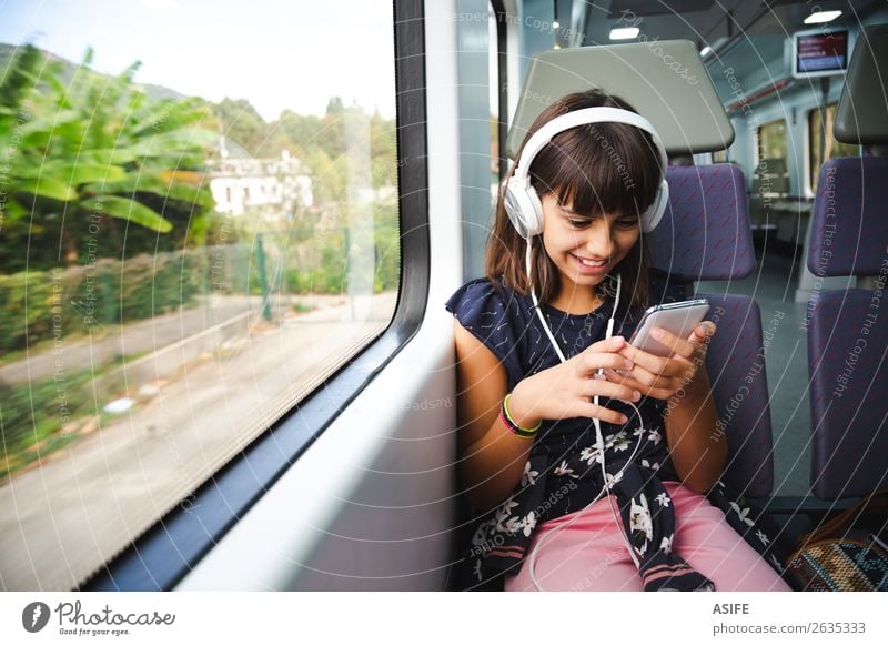 Kleines Mädchen mit Kopfhörer und Smartphone im Zug unterwegs Freude Glück schön Freizeit & Hobby Ferien & Urlaub & Reisen Ausflug Musik Kind Headset PDA