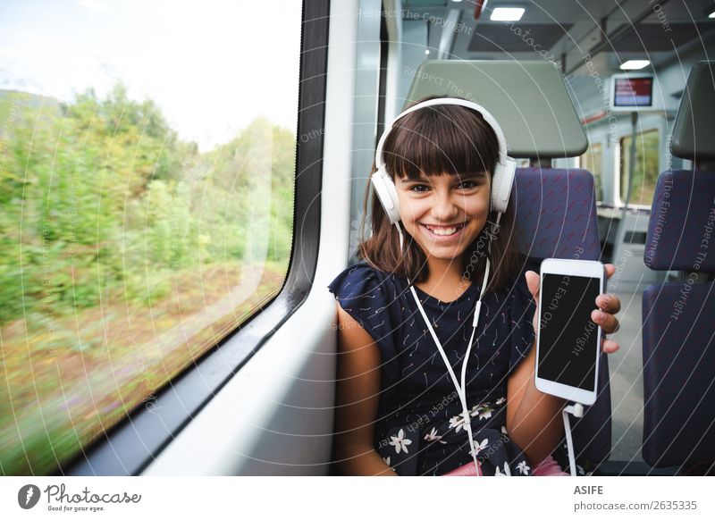 Sie ist glücklich mit ihrem Smartphone, das mit dem Zug fährt. Freude Glück schön Freizeit & Hobby Ferien & Urlaub & Reisen Ausflug Musik Kind Headset PDA