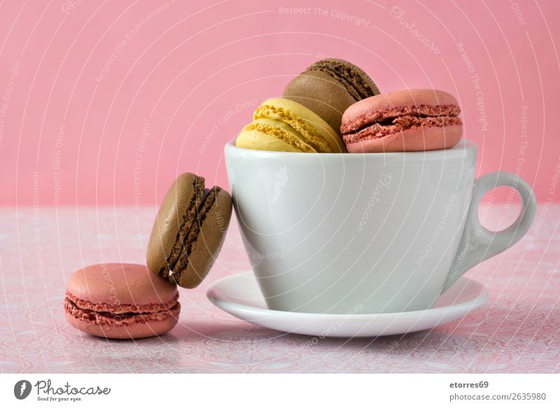 Bunte Makronen in einer Tasse auf rosa Hintergrund Macaron Erdbeeren Zitrone Dessert Kaffee gelb Schokolade Konfekt Himbeeren Tradition Süßwaren