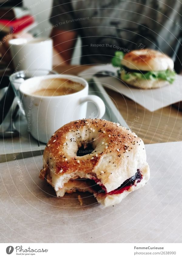 Two people having breakfast bagels in a cafe Lifestyle Junger Mann Jugendliche Erwachsene 1 Mensch genießen Bagel abgebissen Kaffee Café Frühstück Gesundheit