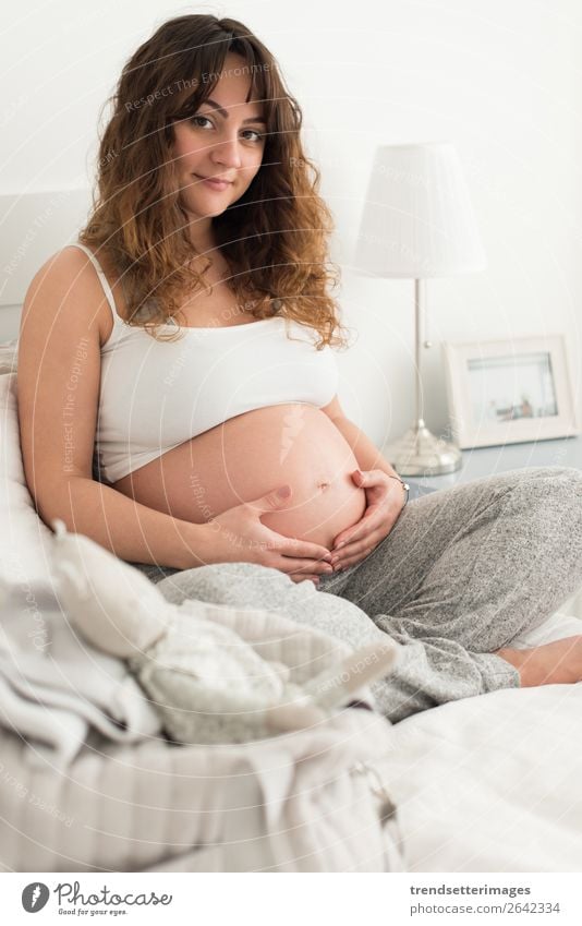 Schwangere Frau, die ihren Bauch berührt. Lifestyle Glück schön Leben Freizeit & Hobby Sofa Mensch Baby Erwachsene Eltern Mutter Familie & Verwandtschaft