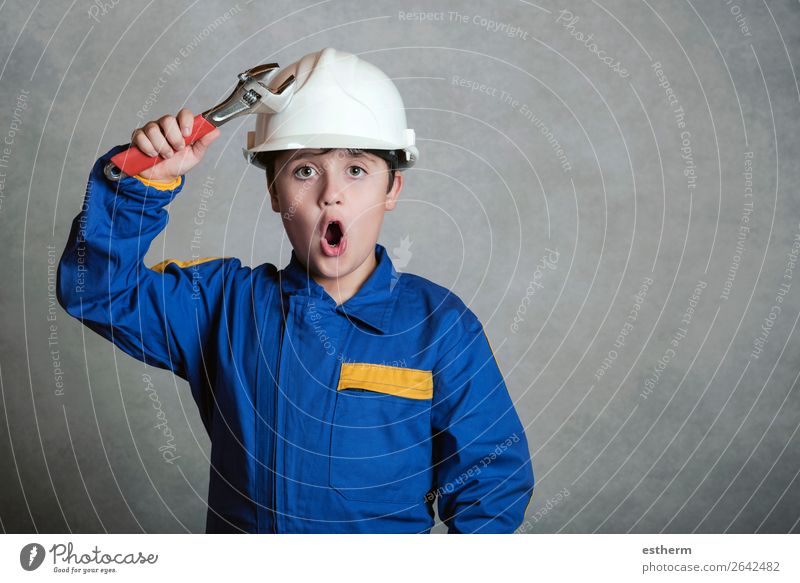 überraschtes Kind mit einem weißen Helm und einem Schraubenschlüssel. Freude Arbeit & Erwerbstätigkeit Baustelle Werkzeug Hammer Mensch Junge Vater Erwachsene