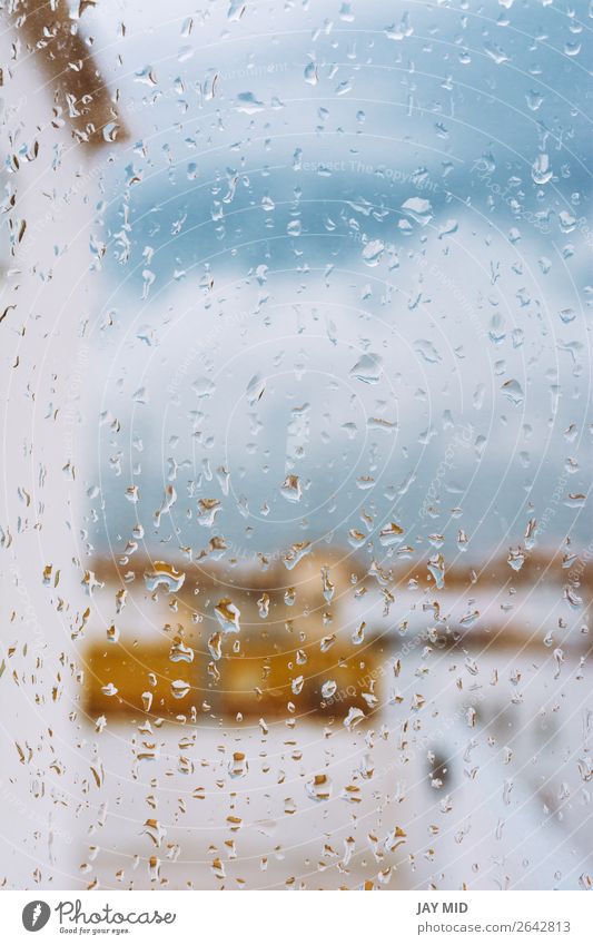 Fenster mit Regentropfen darauf mit Blick auf die Terrasse. Stürmischer Himmel. Wolken schlechtes Wetter Unwetter Traurigkeit trist grau Farbe heimwärts kalt