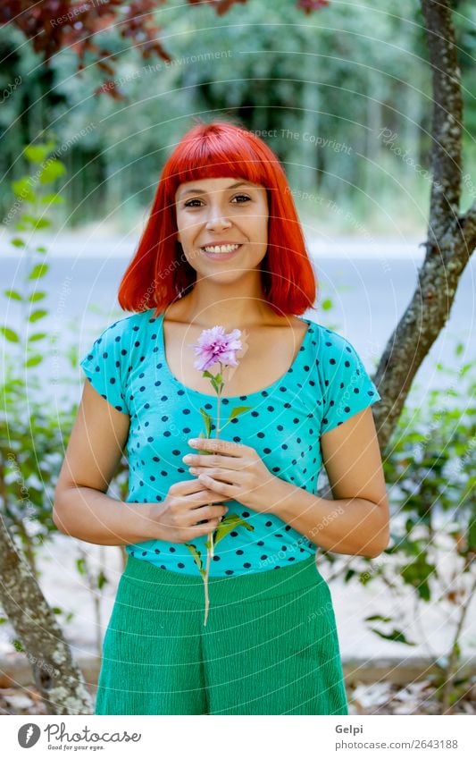 Rothaarige Frau, die eine Blume in einem Park riecht. Lifestyle Glück schön Gesicht Wellness Erholung Duft Sommer Garten Mensch Erwachsene Natur Baum Blüte Mode