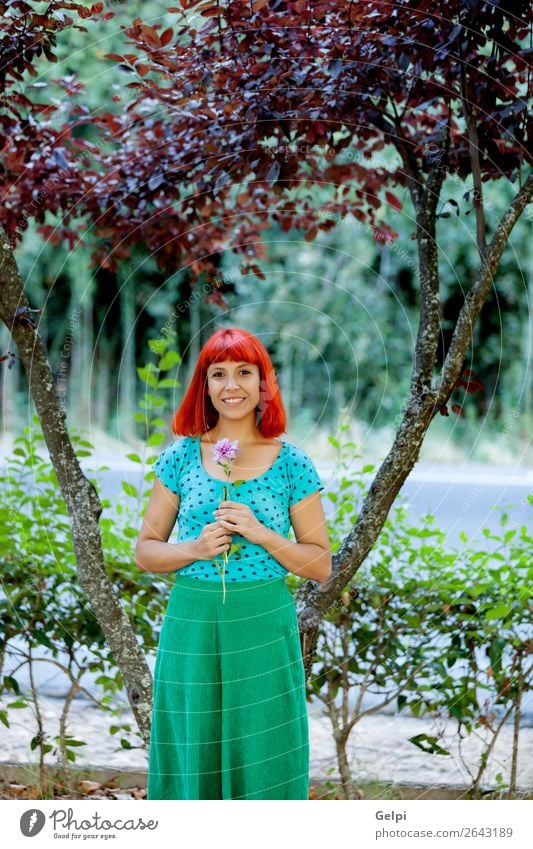 Rothaarige Frau, die eine Blume in einem Park riecht. Lifestyle Glück schön Gesicht Wellness Erholung Duft Sommer Garten Mensch Erwachsene Natur Baum Blüte Mode