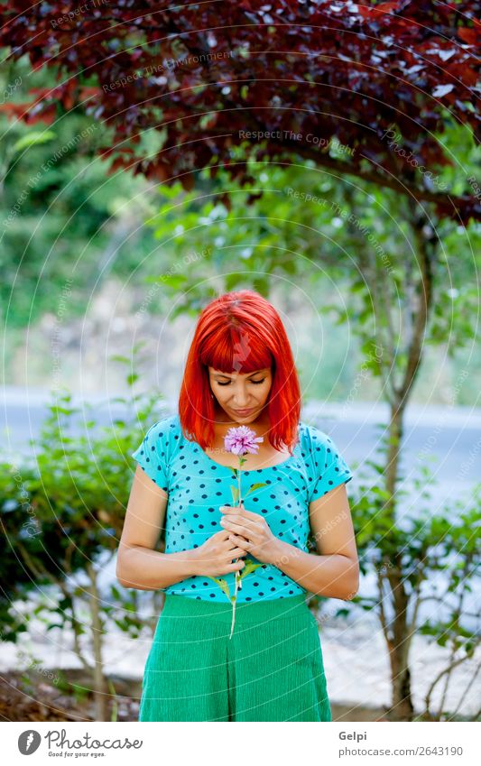 Rothaarige Frau, die eine Blume in einem Park riecht. Lifestyle Glück schön Gesicht Wellness Erholung Duft Sommer Garten Mensch Erwachsene Natur Baum Blüte Mode