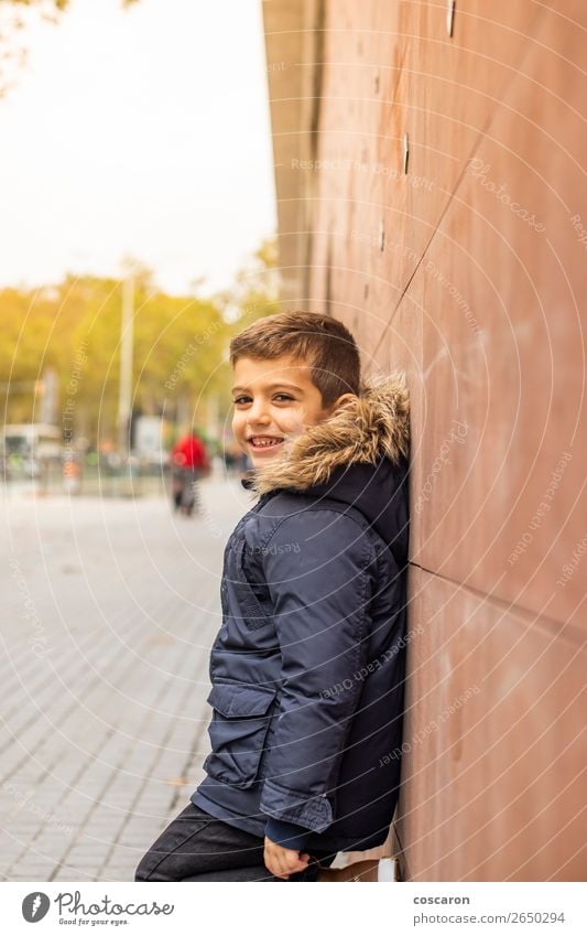 Kleiner Junge, der sich an eine Wand lehnt. Urbane Szene. Lifestyle Stil Glück schön Tourismus Winter Winterurlaub Kind Mensch Baby Kleinkind Mann Erwachsene