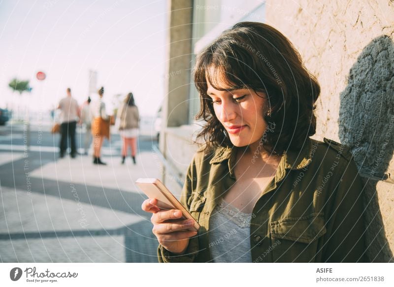 Junge Frau benutzt ihr Smartphone auf der Straße bei Sonnenuntergang. Glück schön Freizeit & Hobby Telefon Handy PDA Technik & Technologie Erwachsene Herbst