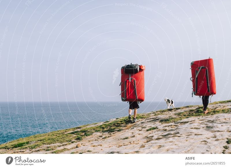 Ein paar Kletterer, die mit Crash-Pads an der Küste laufen. Freude Freizeit & Hobby Abenteuer Meer Berge u. Gebirge wandern Sport Klettern Bergsteigen Frau