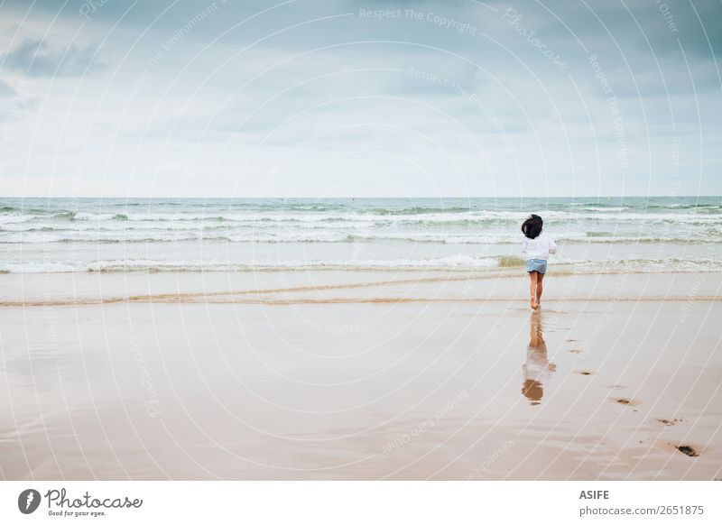 Mädchen genießt den Strand bei schlechtem Wetter Freude Meer Wellen Sport Kind Kindheit Natur Landschaft Sand Himmel Wolken schlechtes Wetter Fußspur genießen