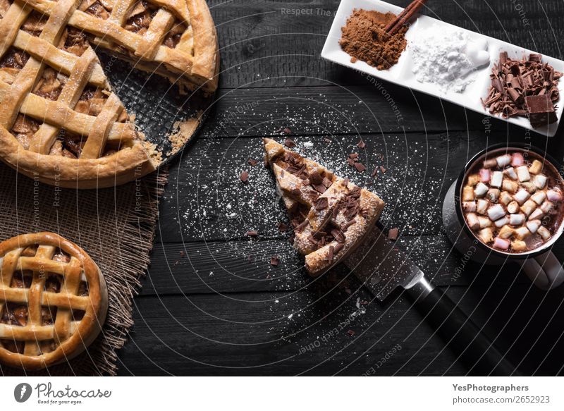 Apfelkuchen mit Scheibe und heißer Schokolade. Kuchen Dessert Süßwaren Kakao Teller Tasse Messer Tisch Küche schwarz Tradition Erntedankfest obere Ansicht