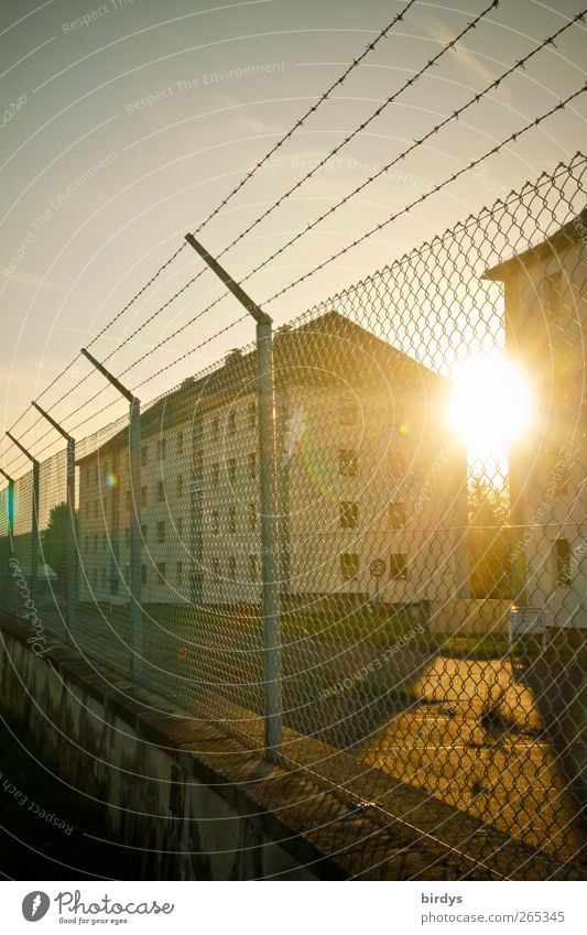 Mit Zaun und Stacheldraht eingezäuntes Kasernengelände oder Wohnkomplex im Gegenlicht der Abendsonne Sicherheit Schönes Wetter Reihenhaus Militärgebäude Sonne