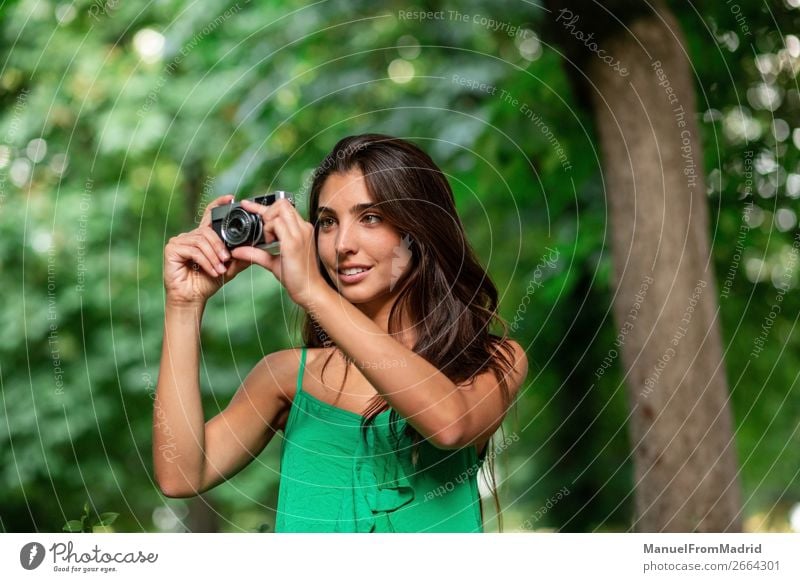 junge schöne Touristenfrau mit einer Fotokamera Lifestyle Glück Ferien & Urlaub & Reisen Tourismus Sommer Mensch Frau Erwachsene Baum Park Straße Mode Hut