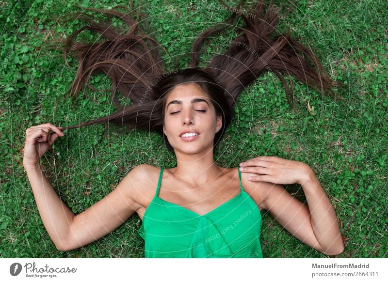 junge, fröhliche Frau, die sich auf das Gras legt. Lifestyle Glück schön Freizeit & Hobby Sommer Mensch Erwachsene Natur Park Wiese Lächeln authentisch