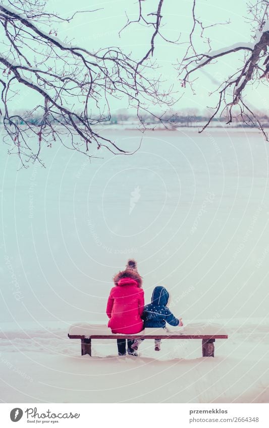 Mutter und ihre Tochter sitzen an winterlichen Tagen auf einer Bank. Lifestyle Freude Glück Winter Schnee Winterurlaub Mensch Kind Kleinkind Mädchen Junge Frau