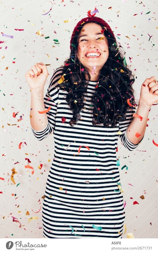 Lachendes Mädchen mit gestreiftem Kleid und Wollmütze unter einem Konfettiregen Freude Glück schön Feste & Feiern Geburtstag Frau Erwachsene brünett Lächeln