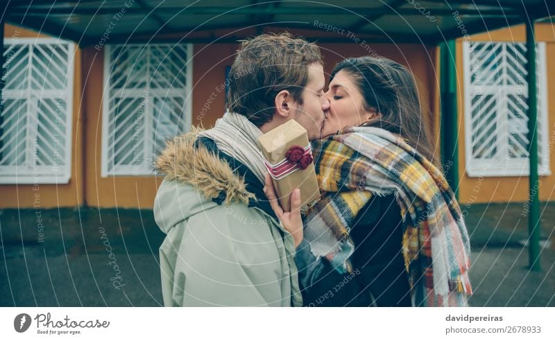 Frau mit Geschenkbox in der Hand, die den Freund umarmt und küsst. Lifestyle Glück schön Winter Feste & Feiern Geburtstag Mensch Erwachsene Mann Paar Herbst