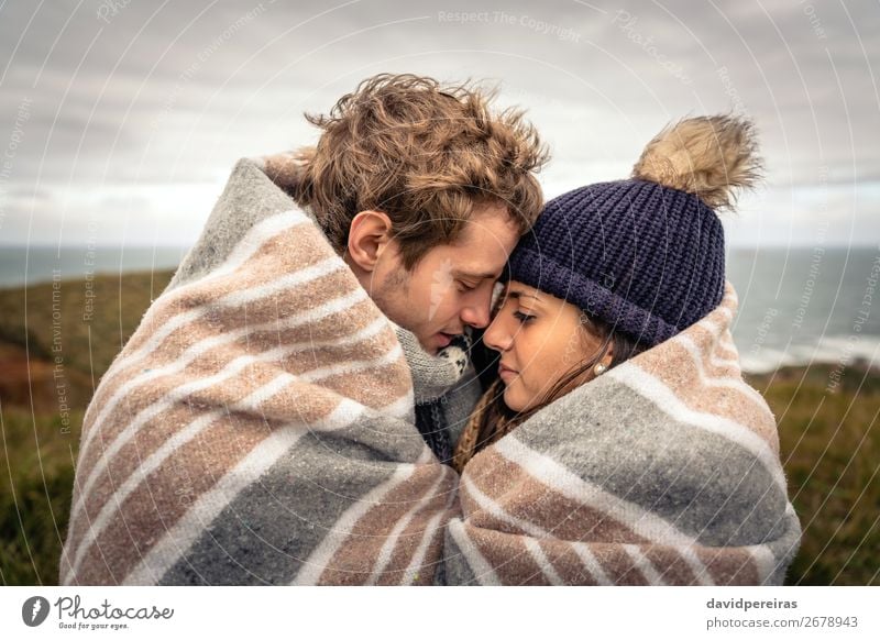 Junges Paar, das sich an einem kalten Tag unter der Decke im Freien umarmt. Lifestyle schön Meer Winter Berge u. Gebirge Frau Erwachsene Mann Natur Himmel