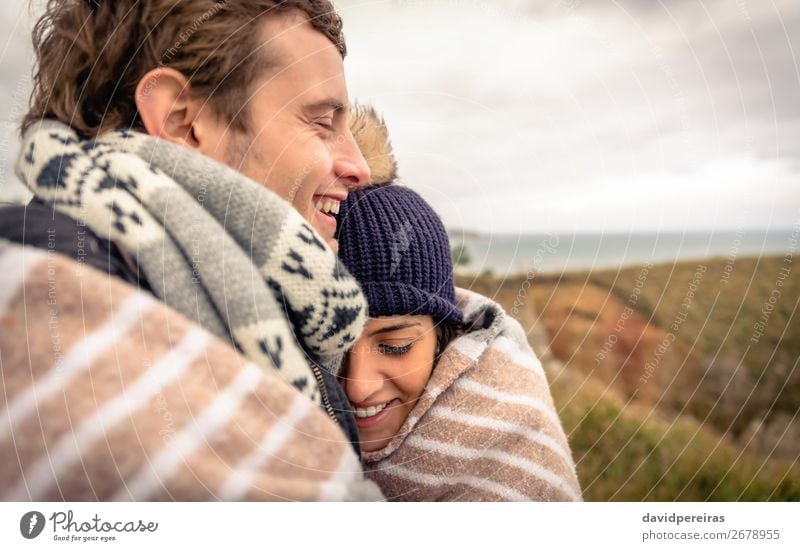 Junges Paar, das an einem kalten Tag unter der Decke im Freien lacht. Lifestyle Glück schön Meer Winter Berge u. Gebirge Frau Erwachsene Mann Natur Himmel