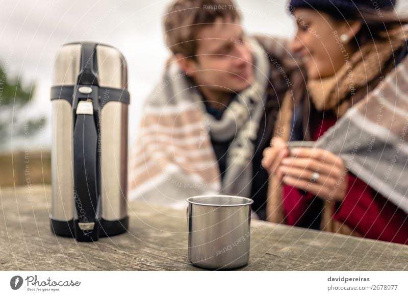 Tasse und Thermoskanne in Tabelle mit Paar unter Decke verschwommen auf Hintergrund Getränk Kaffee Tee Lifestyle Glück Winter Tisch Frau Erwachsene Mann Hand