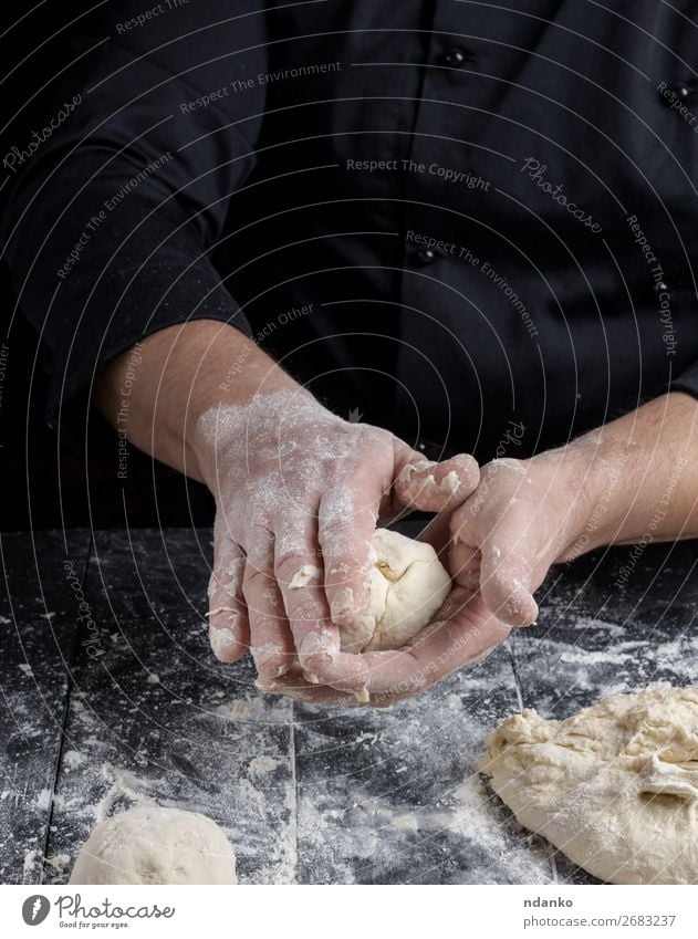 kochen und Teigkugeln auf einem schwarzen Holztisch zubereiten. Teigwaren Backwaren Brot Ernährung Haut Tisch Küche Mensch Mann Erwachsene Hand machen weiß