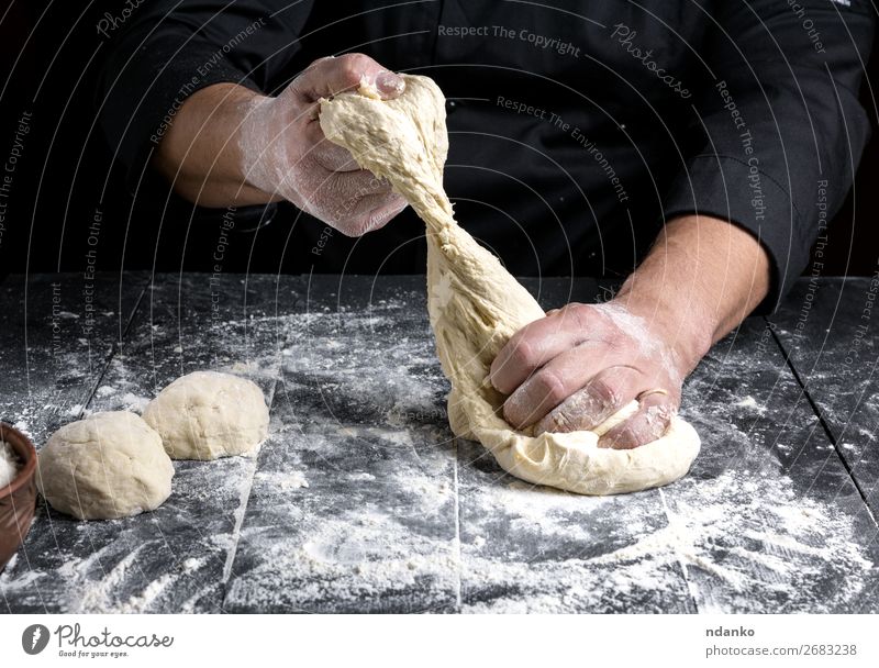 Chefkoch knet Teig aus Weizenweißmehl Teigwaren Backwaren Brot Ernährung Haut Tisch Küche Mensch Mann Erwachsene Hand Holz machen schwarz Tradition backen