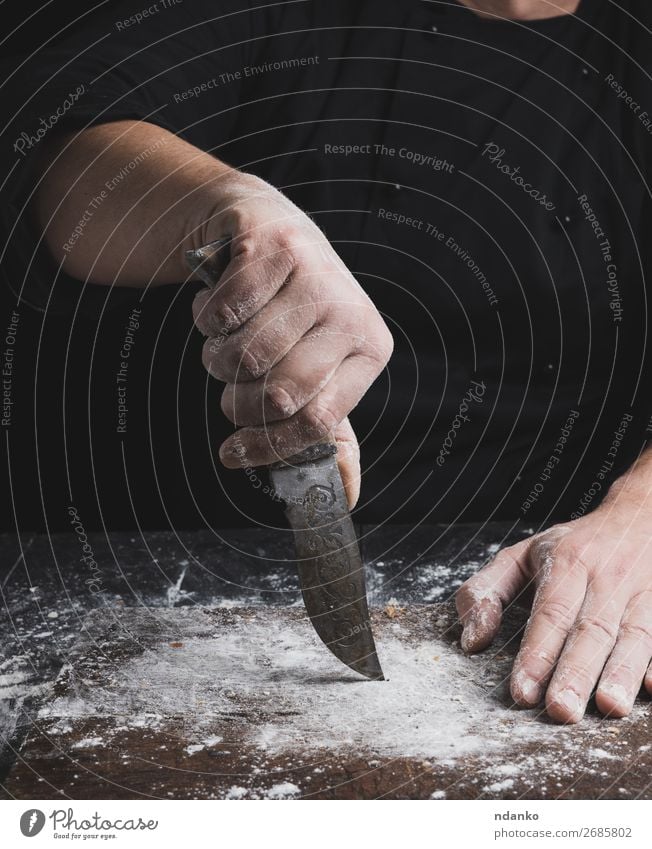 Koch in schwarzer Kleidung mit einem alten alten Messer Teigwaren Backwaren Brot Tisch Küche Mensch Hand Finger Holz machen braun Bäckerei Küchenchef gebastelt