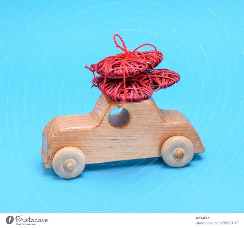 kleines hölzernes Kinderauto trägt ein weidenrotes Herz Feste & Feiern Valentinstag PKW Spielzeug Holz alt Bewegung Liebe tragen natürlich retro blau gelb Idee