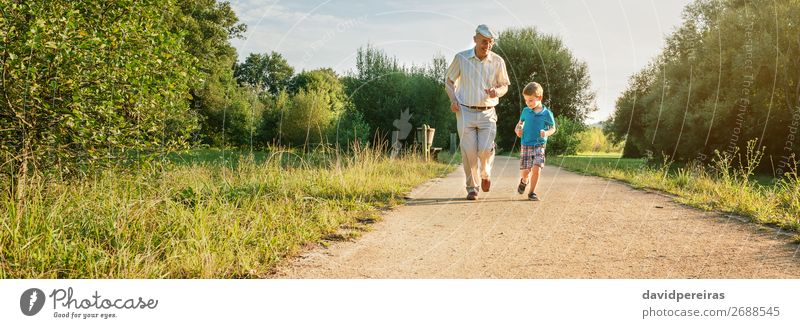 Älterer Mann und glückliches Kind laufen auf Naturpfad Freude Glück Spielen Mensch Junge Erwachsene Großvater Familie & Verwandtschaft Kindheit Baum Park Hut