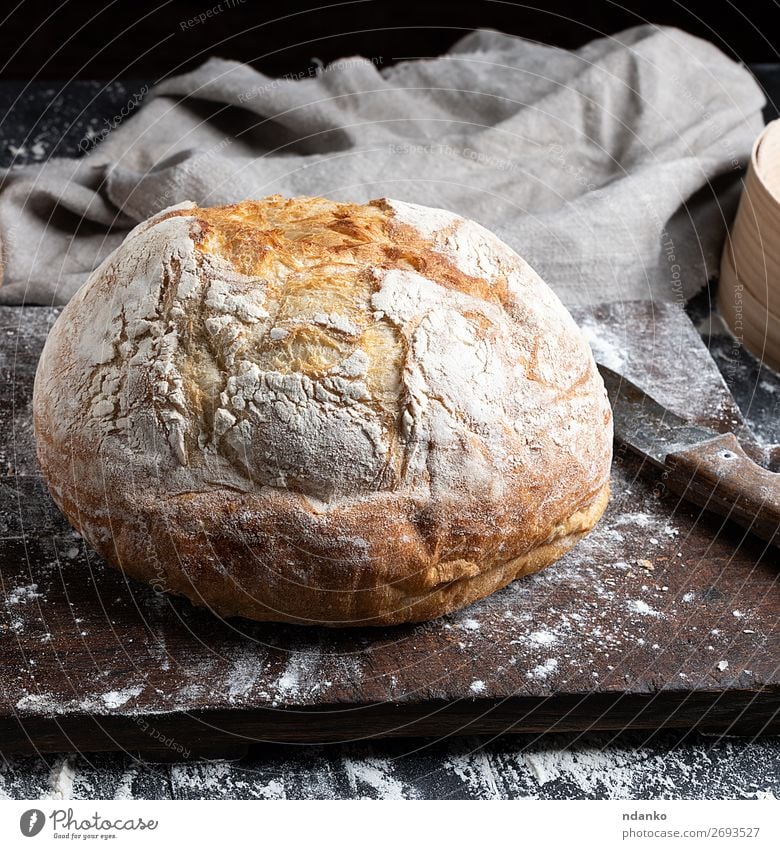 ganzes gebackenes Rundbrot Brot Ernährung Messer Tisch Küche Holz machen dunkel frisch braun schwarz weiß Tradition Bäckerei Holzplatte Essen zubereiten