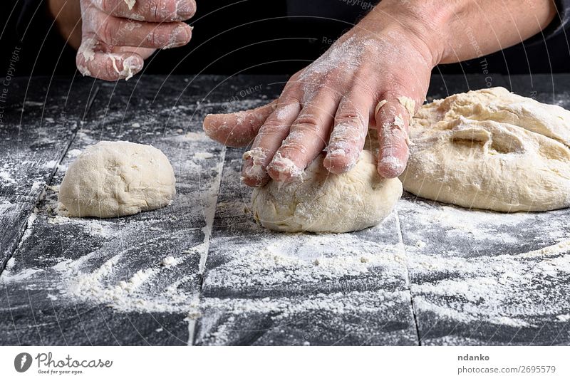 kochen und Teigkugeln auf einem schwarzen Holztisch zubereiten. Teigwaren Backwaren Brot Ernährung Haut Tisch Küche Koch Mensch Mann Erwachsene Hand machen weiß