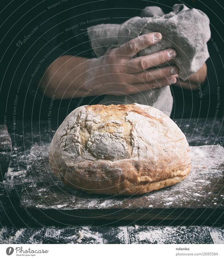 gebackenes Rundbrot auf einem Brett Brot Ernährung Tisch Küche Mensch Hand Finger Holz machen dunkel frisch braun schwarz weiß Tradition Bäcker Bäckerei