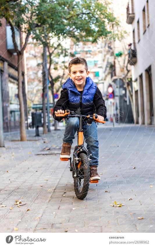 Kleines Kind fährt mit dem Fahrrad auf der Stadtstraße. Lifestyle Freude Glück schön Erholung Freizeit & Hobby Spielen Kinderspiel Sonne Winter Sport