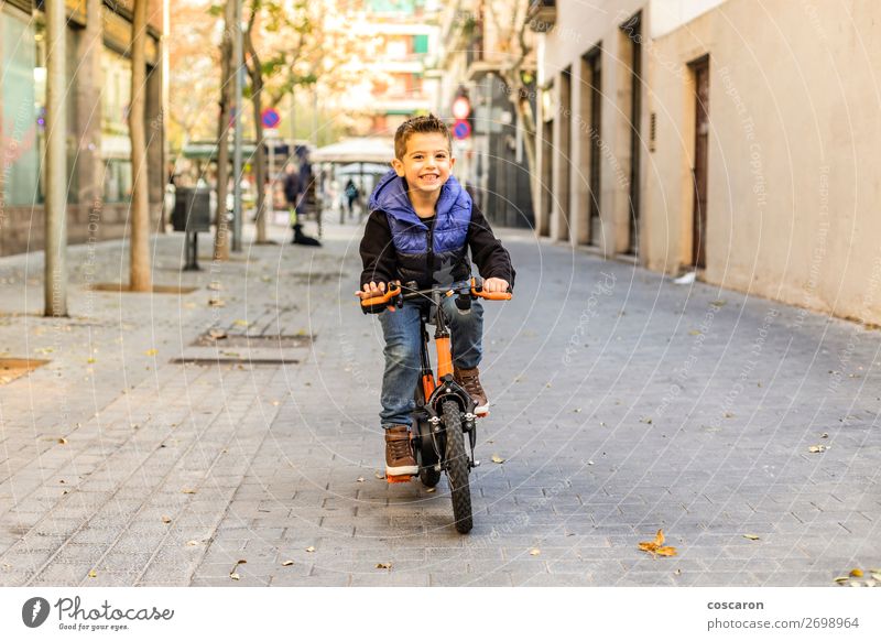 Kleines Kind fährt mit dem Fahrrad auf der Stadtstraße. Lifestyle Freude Glück schön Gesicht Erholung Freizeit & Hobby Spielen Sonne Winter Sport Erfolg